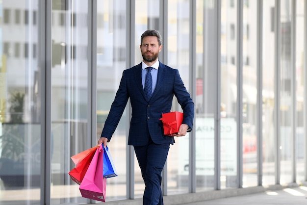 Hombre de negocios, proceso de llevar, bolsas de compras, ambulante, en, ciudad