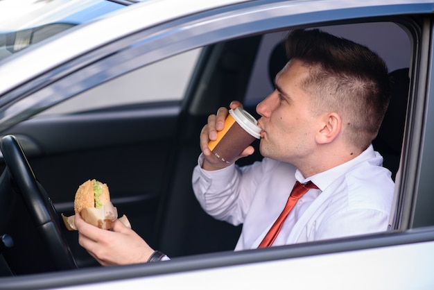 Hombre de negocios que almuerza y toma café en el coche.