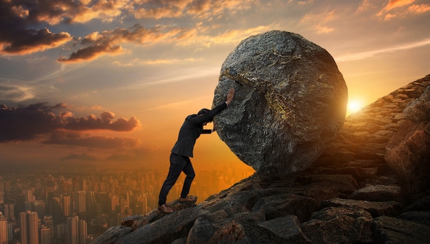 Foto hombre de negocios que empuja la piedra grande hasta la colina, tareas pesadas del negocio y concepto de los problemas.