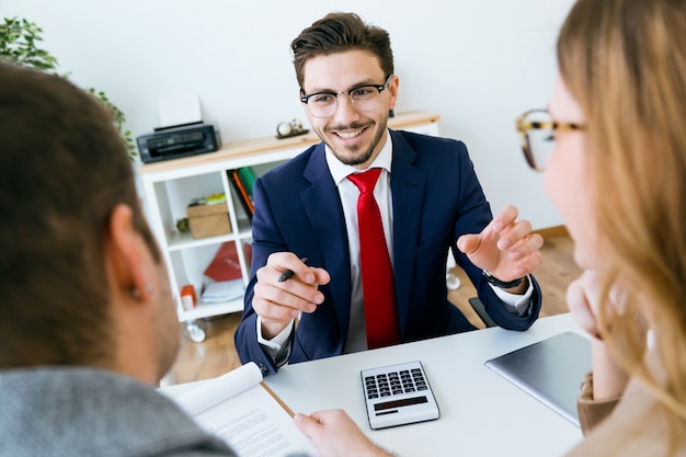 Hombre de negocios que explica los términos del contrato a sus clientes en la oficina.