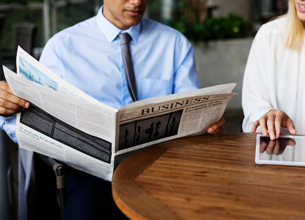 Foto hombre de negocios que lee el periódico y la mujer de negocios que usa una tableta