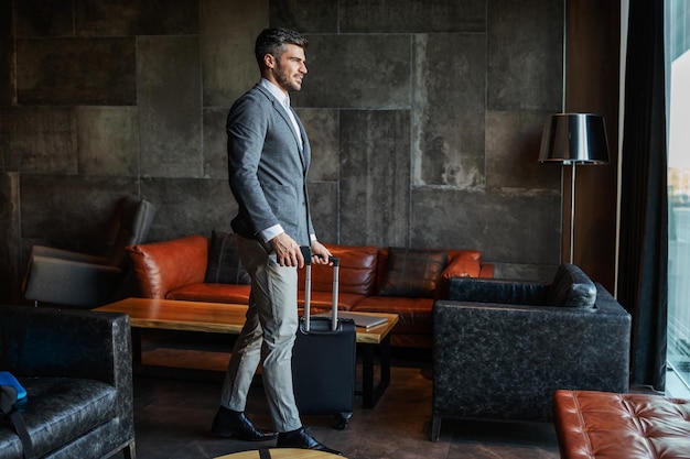 Un hombre de negocios que lleva su equipaje en el vestíbulo de un hotel moderno.