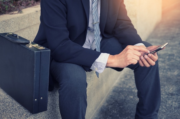 Hombre de negocios que llevaba traje negro y el uso de teléfonos inteligentes modernos en exteriores