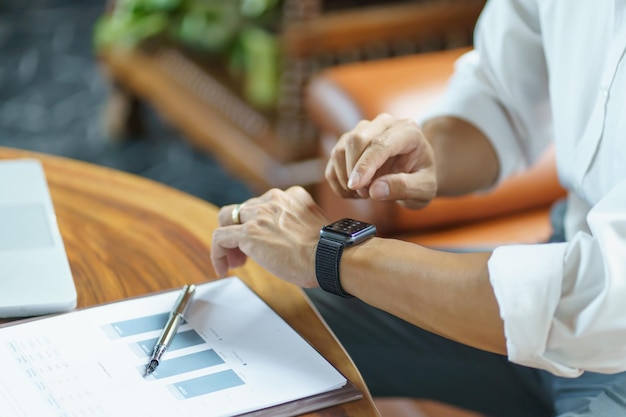 Hombre de negocios que mira el reloj inteligente en la oficina en línea conecta la tecnología Gadget