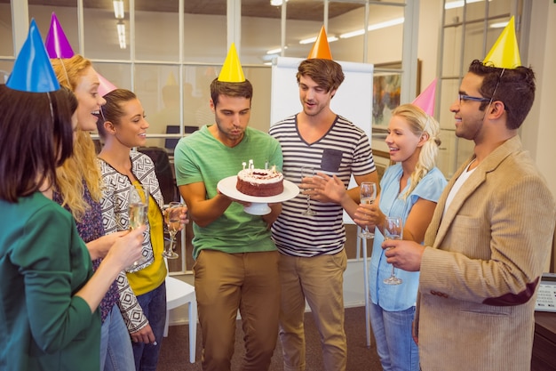 Hombre de negocios que sopla velas en su pastel de cumpleaños