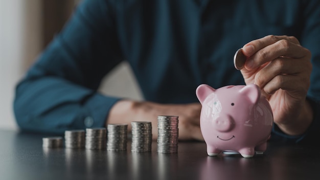 Un hombre de negocios que sostiene una moneda en una alcancía Colocar monedas en una fila de menor a mayor es comparable a ahorrar dinero para crecer más El concepto de aumentar los ahorros y ahorrar invirtiendo en fondos de acciones