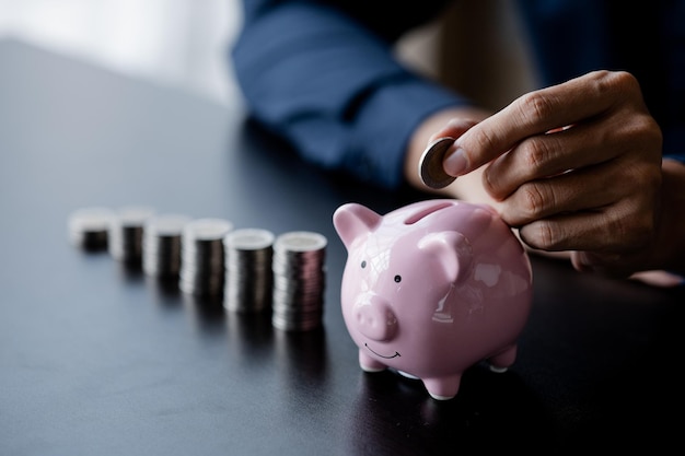 Un hombre de negocios que sostiene una moneda en una alcancía Colocar monedas en una fila de menor a mayor es comparable a ahorrar dinero para crecer más El concepto de aumentar los ahorros y ahorrar invirtiendo en fondos de acciones