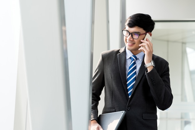 Hombre de negocios que sostiene su tableta de la computadora portátil mientras que usa su teléfono. Concepto de negocio.