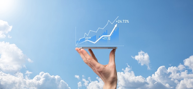 Hombre de negocios que sostiene la tableta y que muestra gráficos holográficos y estadísticas del mercado de valores obtiene ganancias. Concepto de planificación del crecimiento y estrategia empresarial. Visualización de pantalla digital de buena forma económica.