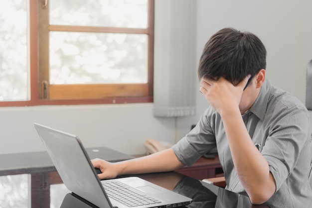 Hombre de negocios que tiene estrés con la computadora portátil que trabaja en la oficina