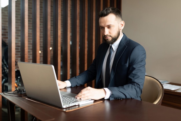 Hombre de negocios que trabaja en una computadora portátil en una oficina elegante con traje