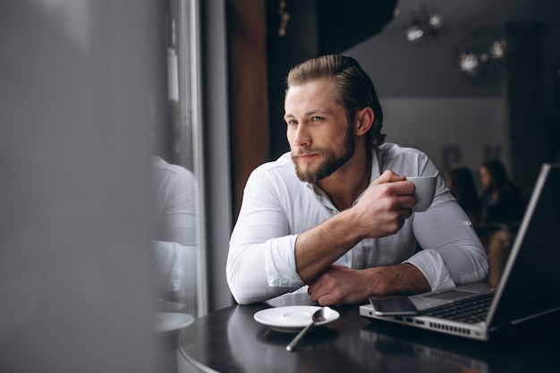 Hombre de negocios que trabaja con la computadora portátil y tomando café en una cafetería