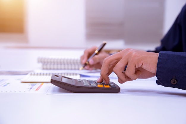 Hombre de negocios que trabaja en un escritorio con una calculadora para calcular.