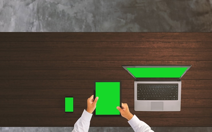 Foto hombre de negocios que trabaja en el escritorio de oficina con pantalla verde de la computadora del teléfono inteligente, tableta y computadora portátil.