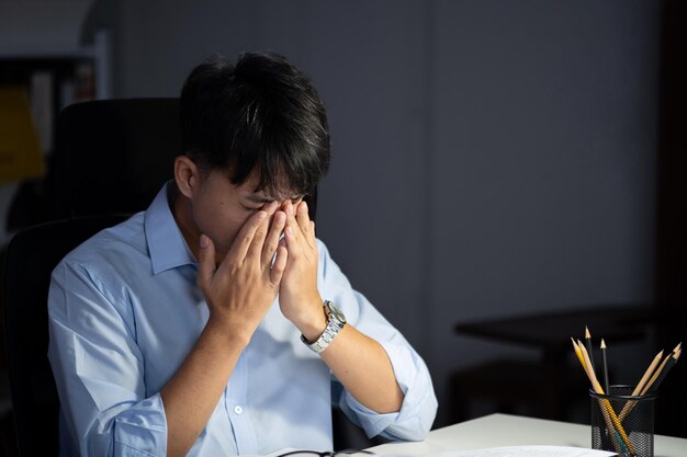 Foto el hombre de negocios que trabaja horas extras en su oficina hace que sus ojos se cansan
