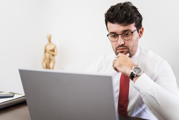 Hombre de negocios que trabaja en la oficina con ordenador portátil y documentos en su escritorio, concepto de abogado consultor.