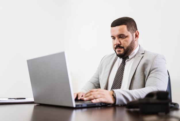 Hombre de negocios que trabaja en la oficina con ordenador portátil y documentos en su escritorio, concepto de abogado consultor.
