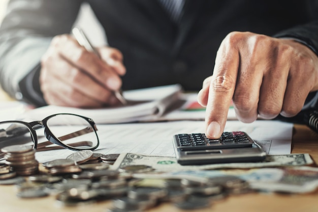 Foto el hombre de negocios que trabaja en oficina usando el calculor para calcula finanzas en el escritorio