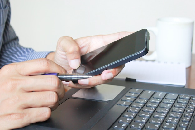 Un hombre de negocios que trabaja en smartphone y la computadora portátil.