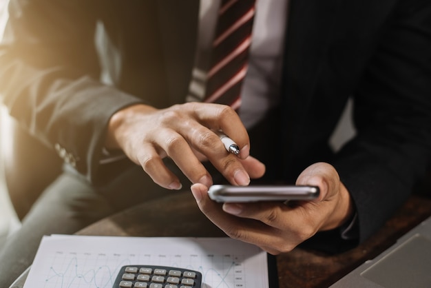 Hombre de negocios que trabaja con teléfonos inteligentes y computadoras portátiles y tabletas digitales en la oficina en casa.