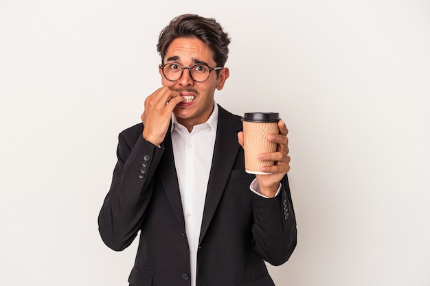 Hombre de negocios de raza mixta joven sosteniendo café para llevar aislado sobre fondo blanco mordiéndose las uñas, nervioso y muy ansioso.