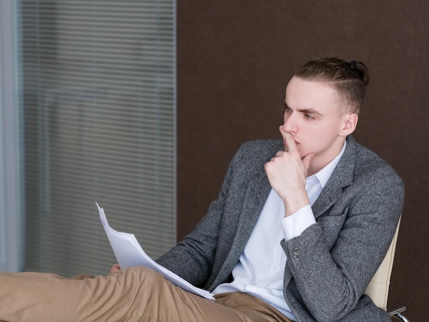 Un hombre de negocios reflexivo y pensativo en el trabajo contemplando los documentos en la oficina, un corredor exitoso y seguro que tiene papeles