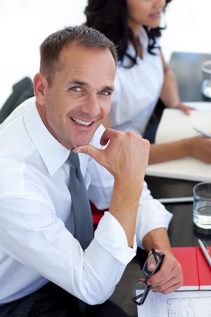 Hombre de negocios en una reunión sonriendo a la cámara