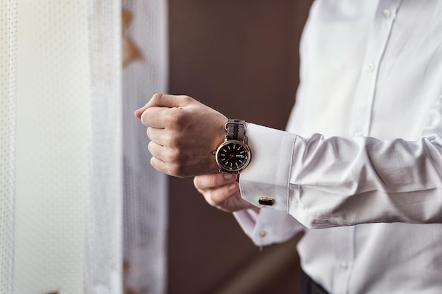 Hombre de negocios revisando el tiempo en su reloj de pulsera hombre poniendo el reloj en el novio preparándose en la mañana antes de la ceremonia de la boda