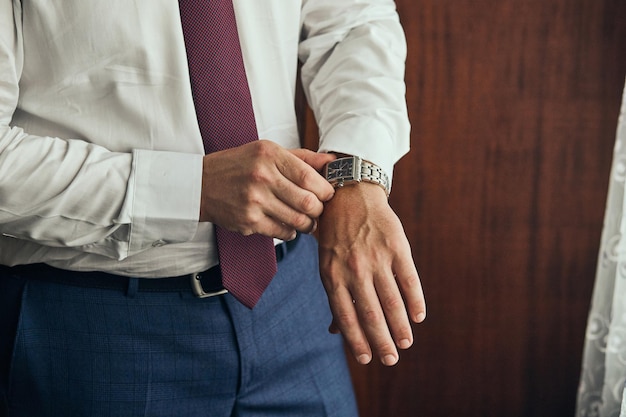 Foto hombre de negocios revisando el tiempo en su reloj de pulsera hombre poniendo el reloj en el novio preparándose en la mañana antes de la ceremonia de la boda