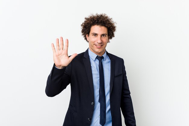 Hombre de negocios rizado joven sonriente alegre mostrando el número cinco con los dedos