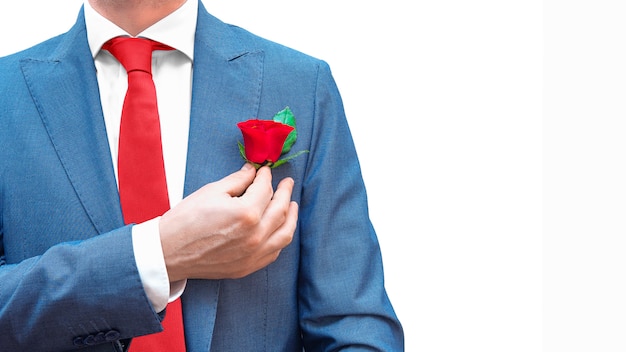 Hombre de negocios romántico en traje azul, corbata roja, camisa blanca con rosa roja en el bolsillo aislado. Copia espacio Código de vestimenta de caballero real.