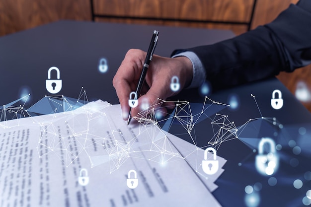 Un hombre de negocios con ropa formal que firma el contrato para evitar la probabilidad de riesgos en la seguridad cibernética Iconos de holograma de candado sobre el escritorio de trabajo