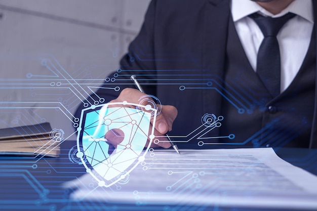 Un hombre de negocios con ropa formal que firma el contrato para evitar la probabilidad de riesgos en la seguridad cibernética Iconos de holograma de candado sobre el escritorio de trabajo