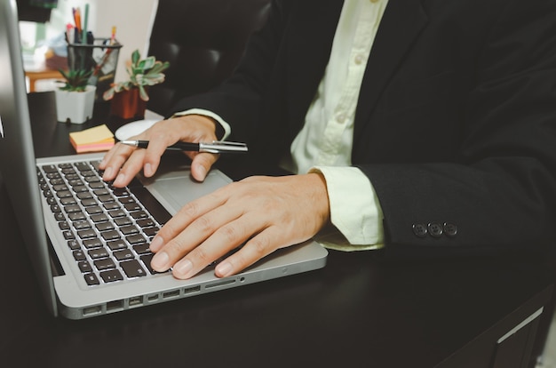 El hombre de negocios seacrh encuentra información en las redes sociales de Internet con una computadora portátil en el escritorio. trabajo para casa.