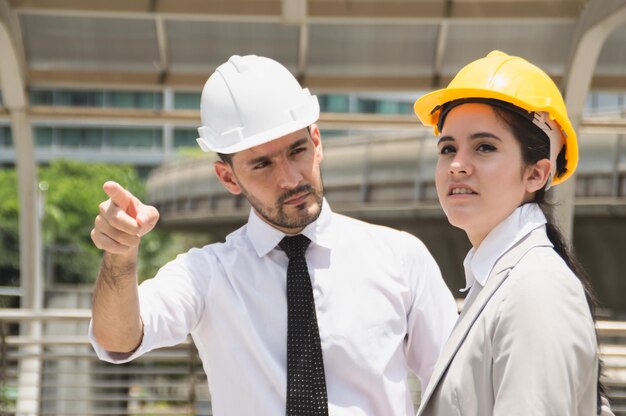 Foto hombre de negocios señalando mientras está de pie con un compañero de trabajo contra el edificio