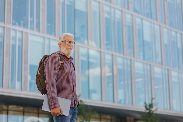 Un hombre de negocios senior con una camisa y una computadora portátil está haciendo una carrera en una gran empresa