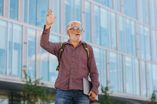 Un hombre de negocios senior con una camisa y una computadora portátil está haciendo una carrera en una gran empresa