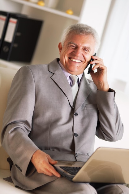 Hombre de negocios senior feliz hablando por teléfono móvil.