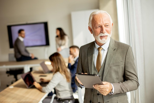 Hombre de negocios senior que trabaja en una tableta digital en la oficina