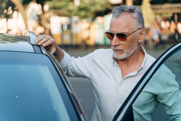 Hombre de negocios senior se sube a su coche después de un duro día de trabajo