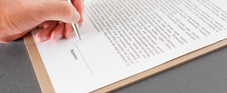 Hombre de negocios sentado en el escritorio de la oficina firmando un contrato con un enfoque superficial en la firma.