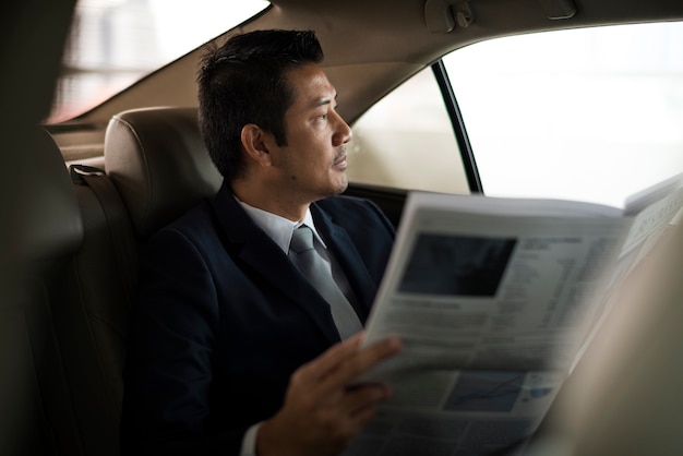 Hombre de negocios, sentado, leer, periódico, dentro, coche