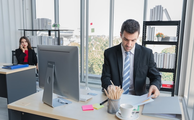 Foto un hombre de negocios está sentado y revisando el papel en la mesa que tiene computadora y documento
