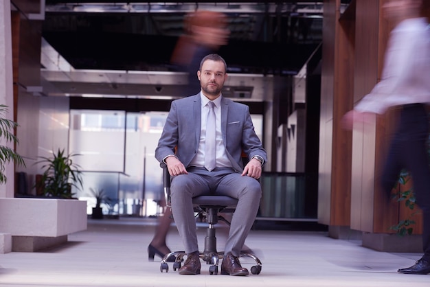 hombre de negocios sentado en una silla de oficina, grupo de personas pasando: Concepto de tiempo, prisa, organización