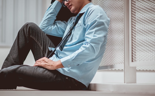 Hombre de negocios sentado en el suelo después del fracaso y el despido Hombre desempleado de la empresa sentado triste