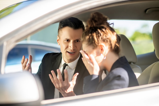 Hombre de negocios serio y mujer llorando en un automóvil