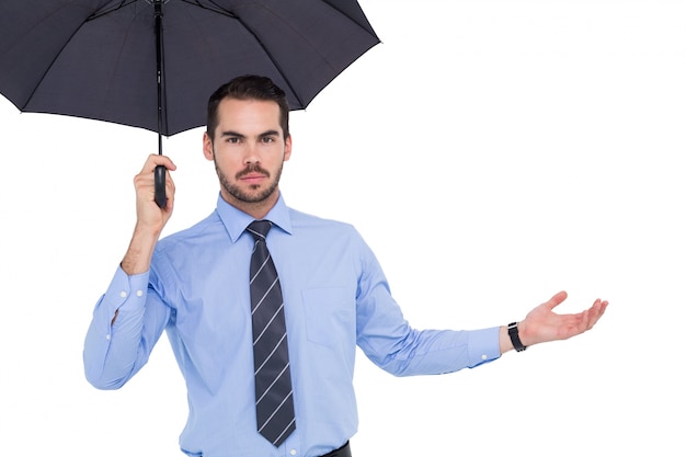 Hombre de negocios serio que sostiene el paraguas con el brazo hacia fuera