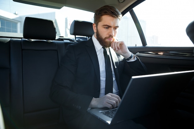 Foto hombre de negocios serio usando la computadora portátil