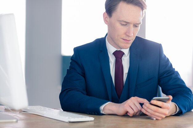 Hombre de negocios serio usando su teléfono inteligente