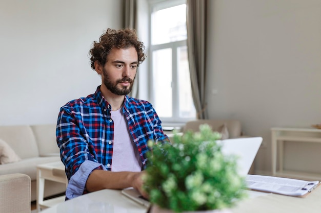 El hombre de negocios se sienta en el escritorio en la oficina mirando datos mientras trabaja en su computadora portátil